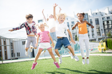 Fototapeta premium Children jumping high while having fun outside after lessons over