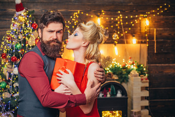 Beautiful Christmas family couple smiling with gift - wish you Happy New Year. Young Christmas fashion couple. Funny couple with colorful make-up and retro hairstyle for Christmas or New Year party.