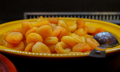 A lot of dried apricots in a bowl on a dark background