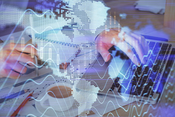 Forex graph with businessman working on computer in office on background. Concept of hardworking. Double exposure.
