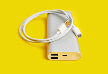 Power bank for charging mobile devices. White smart phone charger with power bank. Battery bank on a yellow background . External battery for mobile devices.