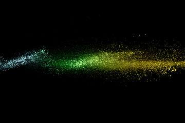 Multi color powder explosion on black background.Blue yellow and green dust cloud in the air.