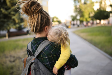 mother with dreadlocks holds tired child on walk