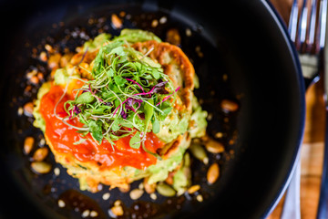 A dish of vegetable patties, Halloumi and Avocado, stacked up on a dark blue plate.