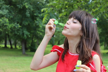 Young brunette woman having fun and blowing bubbles outdoors