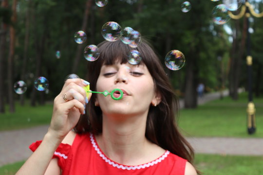 Young brunette woman having fun and blowing bubbles outdoors