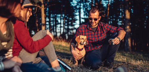 Hiker with friends and his dog resting and drinking coffee