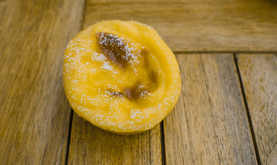 Portuguese custard tart on wooden table, food background