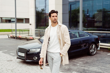 Handsome and stylish business man out of office near to a sportive car