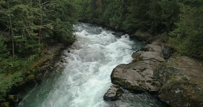 Woman Doing Yoga beside a waterfall in the forest
