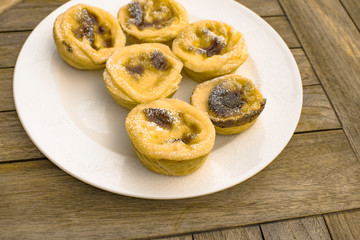 Portuguese custard tart on wooden table, food background