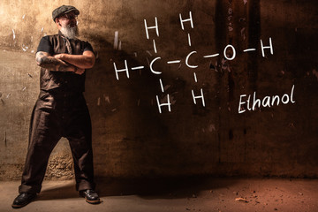 Bearded old man presenting handdrawn chemical formula of ethanol