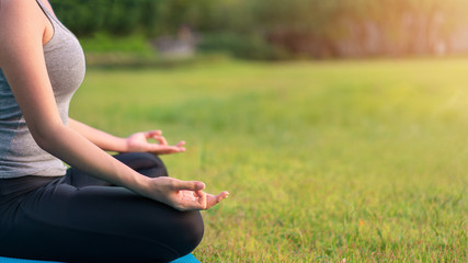 Asian woman meditating and sit in the lotus pose at park, Healthy and Yoga Concept,Mind-body improvements concept, Selective focus, Copy space.