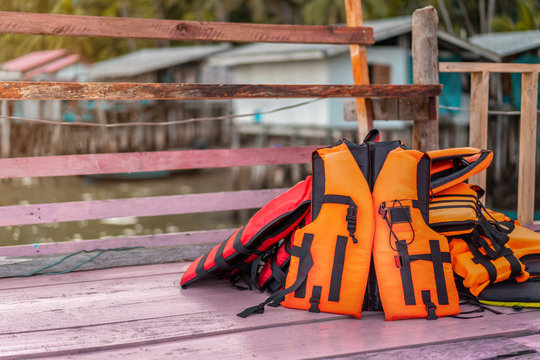 orange life jackets on pink wood with Fishing village background, copy space.