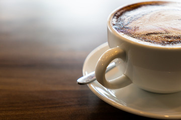 Hot coffee cappuccino latte spiral foam on dark wooden background