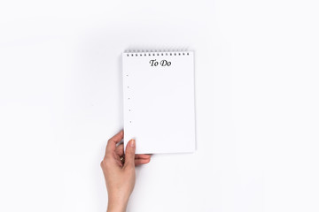 To Do List Concept - 2020 number and text on notepad. Woman's hands with perfect manicure holding  notepad as mockup for your design. White background, flat lay style.