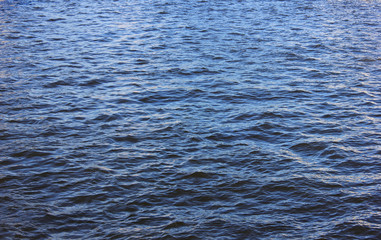 Blue water surface with small waves on calm river background. Dark blue water image with empty copy space