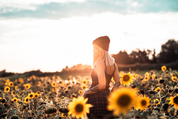 Tätowierte junge Frau abends im Sonnenblumenfeld
