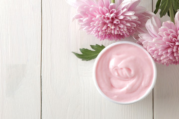 Cream. cosmetics for face and body. Pink cream and flower in a white jar on a white wooden table. top view
