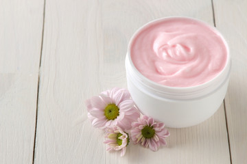 Fototapeta na wymiar Cream. cosmetics for face and body. Pink cream and flower in a white jar on a white wooden table