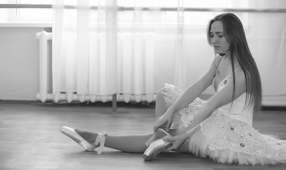 Young ballet dancer on a warm-up. The ballerina is preparing to perform in the studio. A girl in ballet clothes and shoes kneads by the handrails.