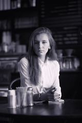 A girl in a cafe is drinking coffee. A woman is having breakfast in a restaurant. Morning coffee in the coffee house for the girl.