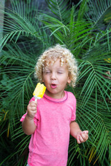  little boy with blonde curly hair is eating ice cream