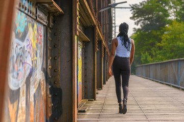 Trendy African woman walking away across a bridge