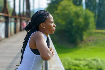 Young African woman standing staring off a bridge