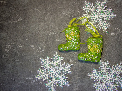 New Year's toys in the form of green Santa Claus boots on a black background with white snowflakes. Fonk both for cards and congratulations.