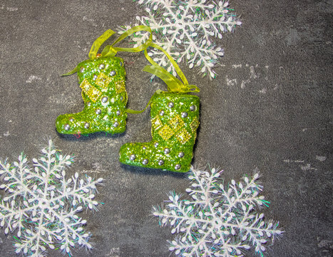 New Year's toys in the form of green Santa Claus boots on a black background with white snowflakes. Fonk both for cards and congratulations.