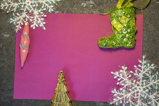 New Year's toys in the form of green Santa Claus boots and other toys on a red and pink background with white snowflakes. Behind black background. Fonk both for cards and congratulations..
