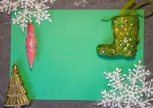 New Year's toys in the form of green Santa Claus boots and other toys on a green background with white snowflakes. Behind black background. Fonk both for cards and congratulations..