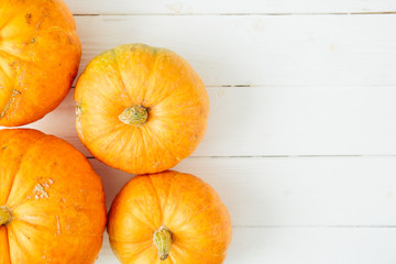 Orange pumpkins on white wooden background with copy space. Thanksgiving and Halloween concept. View from above. Top view. Copy space for text and design