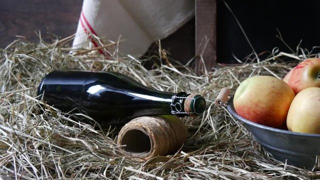 Moving camera slider showing bottle of cider with apples on  straw
