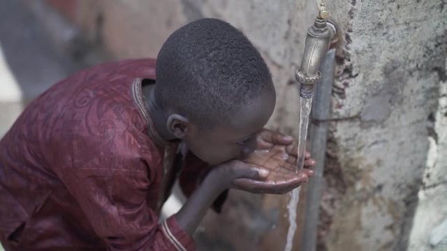 Young African Schoolboy Drinking Fresh Clean Water, Poverty Symbol