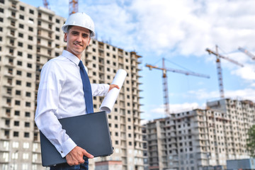 civil engineer in white helmets and white shirt on the background of the house under construction.