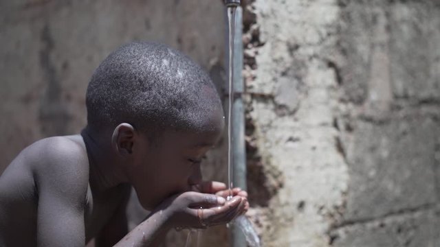 Hygiene Symbol, Little African Black Boy Drinking Fresh Water from tap in Bamako, Mali