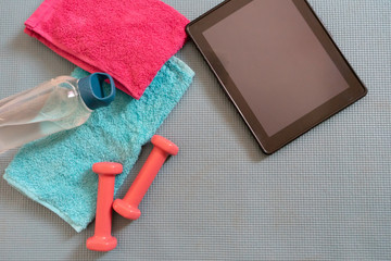 Feminine exercise & fitness equipment and digital tablet. Athletics tools for exercise at home and rehab. Muscle class training. Towel and hydration flat lay