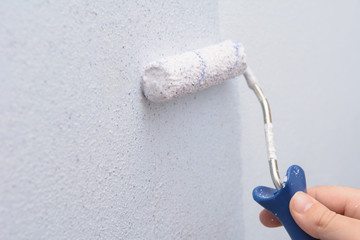 male hand with a roller for painting walls. The painter applies decorative paint to the wall....