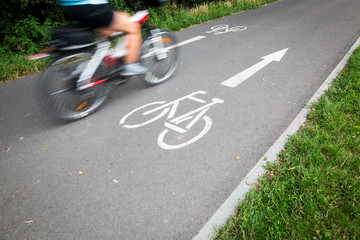 Cyclist on a road bike / bike path going fast (motion blur technique is used to convey movement;...