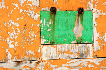 Close up old peeled yellow and green colored wooden wall and window detail of building exterior