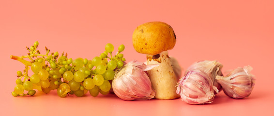Mushroom, grape and garlic on a pink background