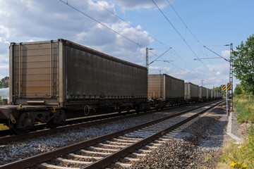 Fototapeta na wymiar Outdoor sunny view of container train or railway freight transportation service, on the countryside in Germany. 