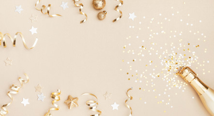 Champagne bottle with confetti stars, holiday decoration and party streamers on gold festive background. Christmas, birthday or wedding concept. Flat lay. - obrazy, fototapety, plakaty
