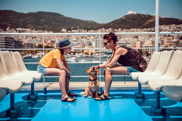 Mother and daughter sitting on the deck of a ferry with a dog