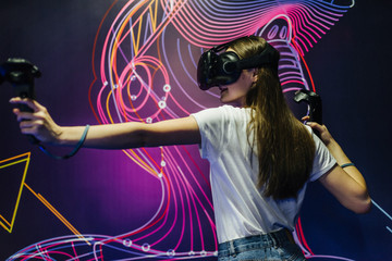 Happy woman with virtual reality headset and joystick playing VR games