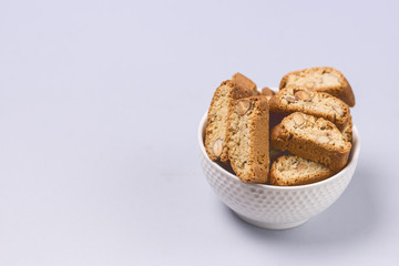 Italian Almond Biscuit Biscotti or Cantuccini in a White Bowl Tasty Italian Dessert for Coffee or Wine Blue Background