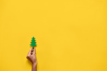 Plastic toy pine wood tree on yellow background. Minimal flat lay of Christmas season. Copy space