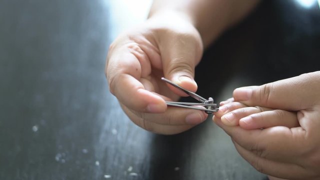 adult or parent and mother cut fingernails for child or kid to long nails and dirty with cleanliness by nail clipper on slow